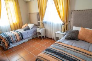 a bedroom with two beds and yellow curtains at Casa Oseleta de Bodega Masi in Tupungato