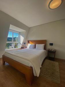 sypialnia z dużym łóżkiem i dużym oknem w obiekcie Flats Chateau Campos do Jordão w mieście Campos do Jordão