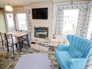 a living room with a blue couch and a table at Beachcomber D35 in Abergele