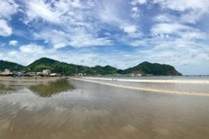a beach with mountains in the background and a cloudy sky at Modern Studio/Apt overlooking Pool/Ocean view in San Juan del Sur