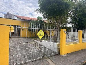 a fence in front of a yellow building with a sign at Suíte Azul com SmartTv, Cama Queen e Banheiro Privativo in Itajaí