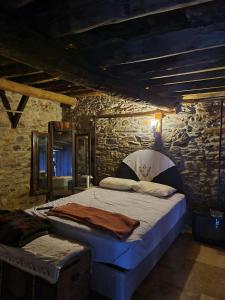 a bedroom with a bed and a stone wall at Helvacılar Konağı in Karacasu