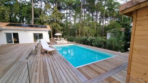 - une piscine sur une terrasse en bois à côté d'une maison dans l'établissement Les Chalets du Golf de Biscarrosse, à Biscarrosse