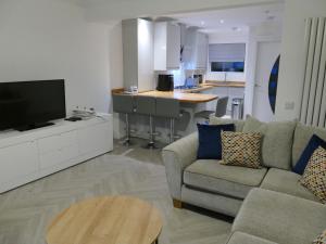 a living room with a couch and a tv and a kitchen at The Annexe in Eaglesham