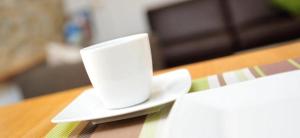a white coffee cup sitting on a plate on a table at Weingut Edling in Roßdorf