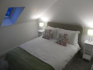 a bedroom with a white bed with pillows and two lamps at The Annexe in Eaglesham