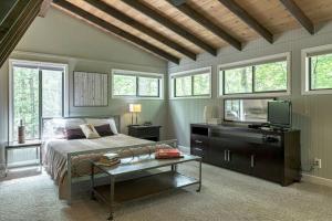 1 dormitorio con 1 cama, TV y ventanas en Treetop Getaway by Sarah Bernard Chalets, en Innsbrook