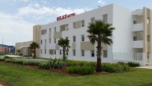 a white building with palm trees in front of it at Relax Hôtel Oujda in Oujda