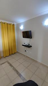 a living room with a tv and yellow curtains at Bliss Escapes in Ruiru