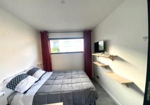 ein kleines Schlafzimmer mit einem Bett und einem Fenster in der Unterkunft Studio atypique Le Mans in Le Mans