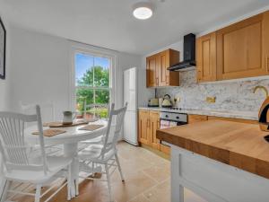 a kitchen with a white table and chairs and a table and a counter at Pass the Keys Spacious and Modern Sea Side apartment in Whitstable