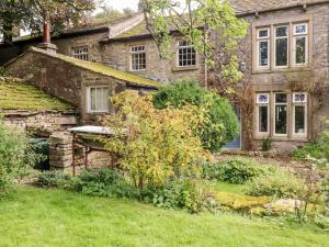 an old stone house with a garden in front of it at Oak Cottage in Skipton