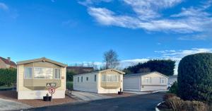 a row of mobile homes parked in a driveway at Red Deer Village Holiday Park - 3 Bedroom, Self-Catering Holiday Home in Steps