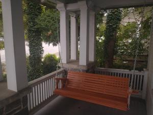 a wooden bench swing on a porch with columns at Blackjack's Bungalow in York