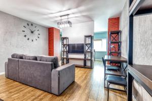 sala de estar con sofá y reloj en la pared en Apartment Severnoye Siyaniye 37, en Astana