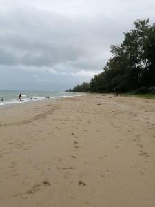 a beach with footprints in the sand and people in the water at RatuSpaQ Home Desaru Utama Residence Apartment in Bandar Penawar
