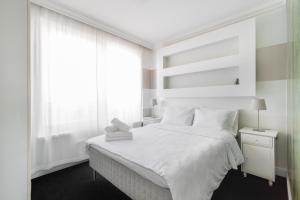 Un dormitorio blanco con una cama blanca y una ventana en Warta River Sleep Well Apartment en Poznan