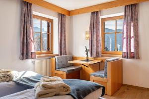 - une chambre avec 2 lits, un bureau et des fenêtres dans l'établissement Häuslerhof App Betula, à Villabassa