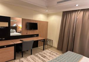 Dormitorio con escritorio, cama y TV en فندق الفرسان en Yeda