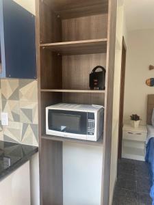 a microwave sitting on a shelf in a kitchen at Segunda Casa- Seu cantinho na Praia do Morro em Guarapari - Quartos suítes 2 até 4 pessoas in Guarapari