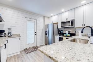 a kitchen with white cabinets and a stainless steel refrigerator at Palm 31 in Myrtle Beach