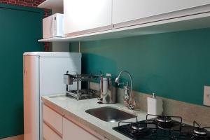 a kitchen with a sink and a white refrigerator at Wine Lovers Apartamento Studio em Bento Gonçalves/RS in Bento Gonçalves