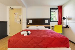 a bedroom with a red bed and a yellow chair at Premiere Classe Bethune Fouquières Lès Béthunes in Fouquières-lès-Béthune