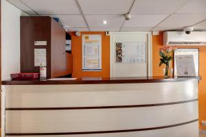 a lobby with a reception counter with flowers at Premiere Classe Bethune Fouquières Lès Béthunes in Fouquières-lès-Béthune