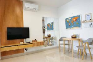 a living room with a tv and a table and chairs at Summer Studio Apartment at Kota Kinabalu City Centre in Kota Kinabalu