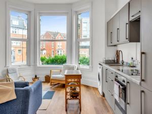 a kitchen with two windows and a blue couch at Pass the Keys Spacious Sea Side apartment in Folkestone