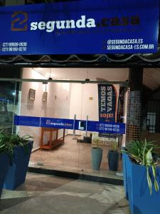 a store front with a blue sign and potted plants at Segunda Casa- Seu cantinho na Praia do Morro em Guarapari - Quartos suítes 2 até 4 pessoas in Guarapari