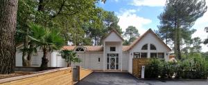 una casa bianca con un albero e una recinzione di Les Chalets du Golf de Biscarrosse a Biscarrosse