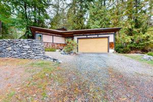 ein Haus mit einer Garage mit einer Steinmauer in der Unterkunft Woodland Cove in Lakebay