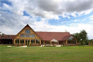 a large wooden building with a large grass field at Country Gem in Tydd Saint Giles