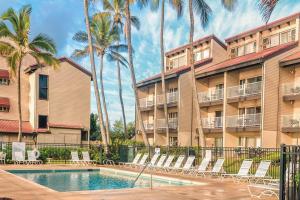 a hotel with a swimming pool and chairs and palm trees at 1BR Condo at Oceanfront Resort Kapaa Shore in Kapaa