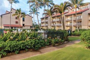 a resort with palm trees and a fence with plants at 1BR Condo at Oceanfront Resort Kapaa Shore in Kapaa
