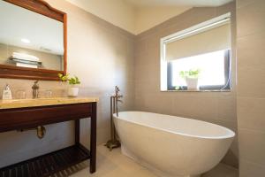 a bathroom with a tub and a sink and a window at Virgo Villa Quê Hội An in Hoi An