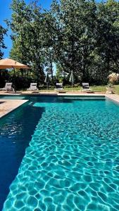 a blue swimming pool with chairs and an umbrella at Château Le Repos - Luxury air-conditioned property with pool in Rouffignac-de-Sigoulès