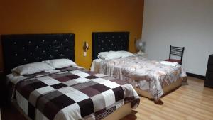1 dormitorio con 2 camas y 1 silla en Venecia Hotel Larco, en Trujillo