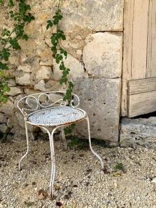 una sedia di metallo seduta di fronte a un muro di pietra di Château Le Repos - Luxury air-conditioned property with pool a Rouffignac-de-Sigoulès
