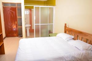 - une chambre avec un lit blanc et une salle de bains dans l'établissement The Penthouse Suites Serviced Apartments Meru, à Meru