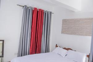 - une chambre avec un lit doté de rideaux rouges et gris dans l'établissement The Penthouse Suites Serviced Apartments Meru, à Meru