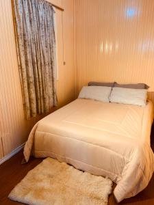a bed in a room with a window and a rug at Aconchegante Casa Serrana ao lado da Igreja Matriz in Urubici