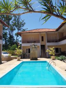 a swimming pool in front of a house at Pousada Baleia Azul in Rio das Ostras