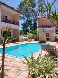 a villa with a swimming pool in front of a house at Pousada Baleia Azul in Rio das Ostras