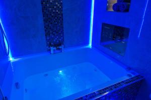 e bagno con vasca e illuminazione blu. di Aphrodite Suites Huddersfield a Huddersfield