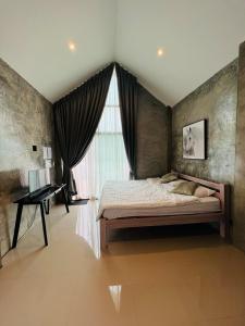 a bedroom with a bed and a window and a desk at ริมยมรีสอร์ท in Ban Wang Din