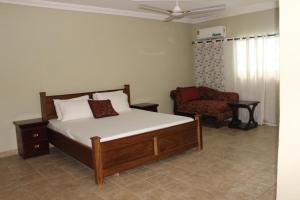 a bedroom with a bed and a chair at FREDA'S COURT in Accra