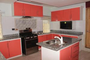 a kitchen with red cabinets and a sink at FREDA'S COURT in Accra