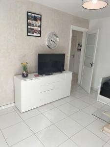 a white living room with a tv and a clock on the wall at Joli appartement proche métro in Lyon